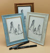 Three framed artworks of rock formations on a beige surface with two black markers.