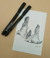 Two black markers and a drawing of a rock formation on a beige surface