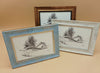 Three framed black and white landscape drawings featuring trees and rocks on a beige background