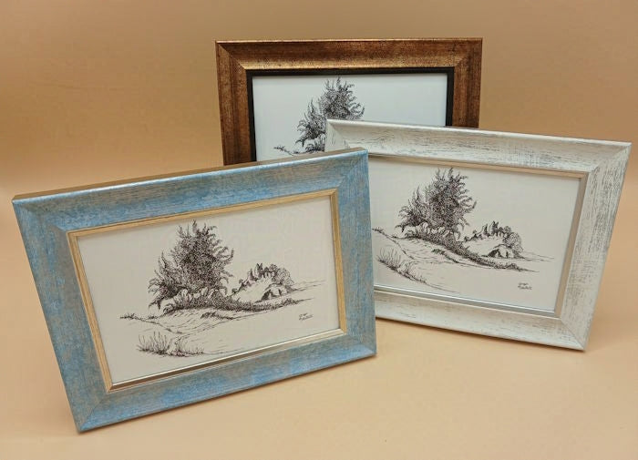 Three framed black and white landscape drawings featuring trees and rocks on a beige background