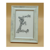 Framed artwork with a decorative letter 'E' on a beige background